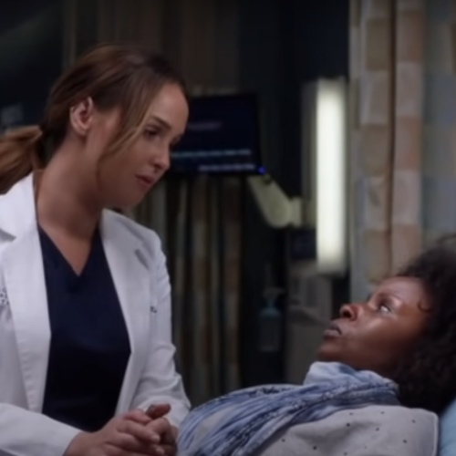 white female nurse holding the hand of a Black woman on a hospital bed